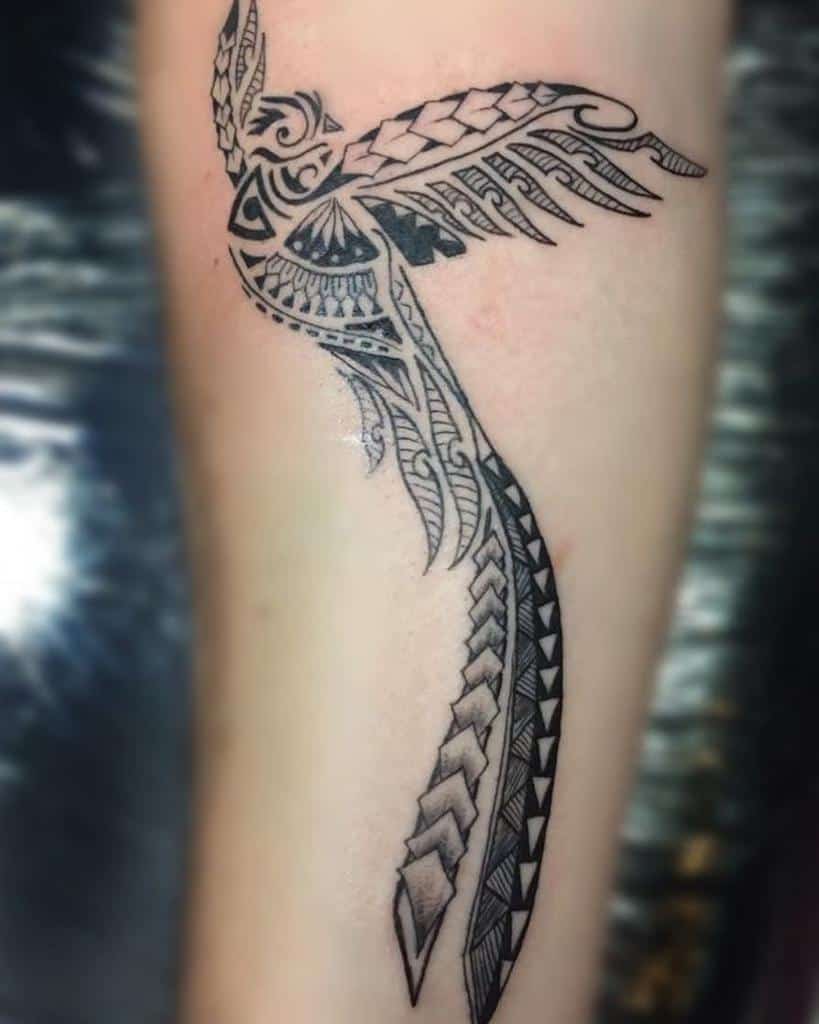 Ornate tribal tattoo of a quetzal with outstretched wings and a long tail on a forearm