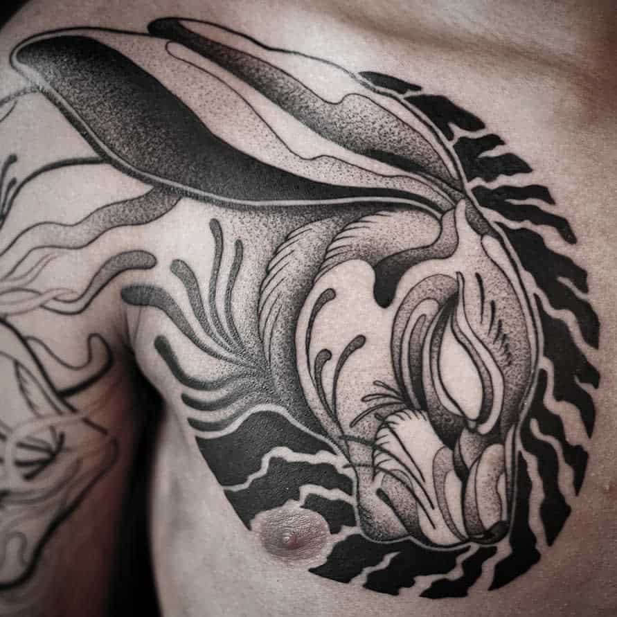 Bold black and gray tattoo of a rabbit with flowing lines and abstract swirls
