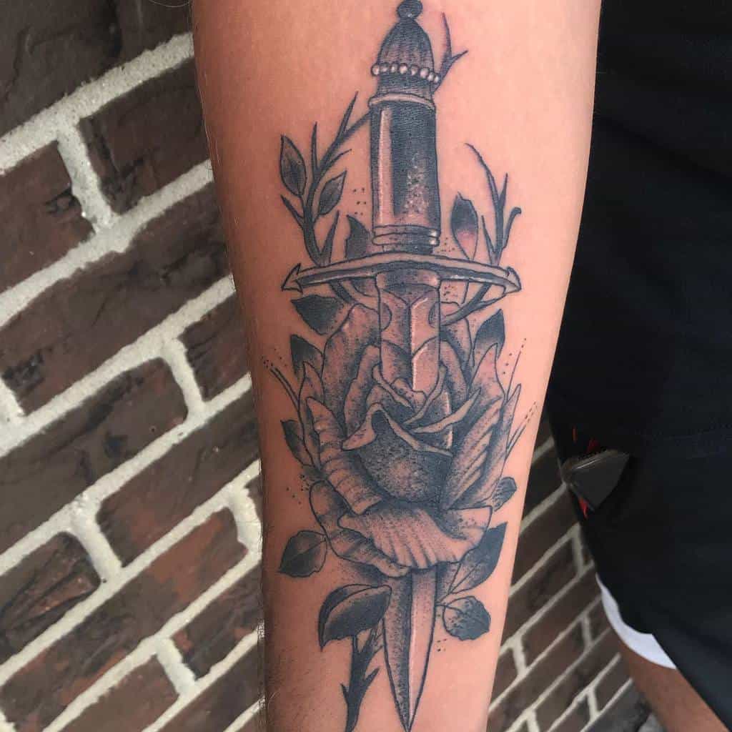 Traditional tattoo of a dagger piercing a rose on a forearm