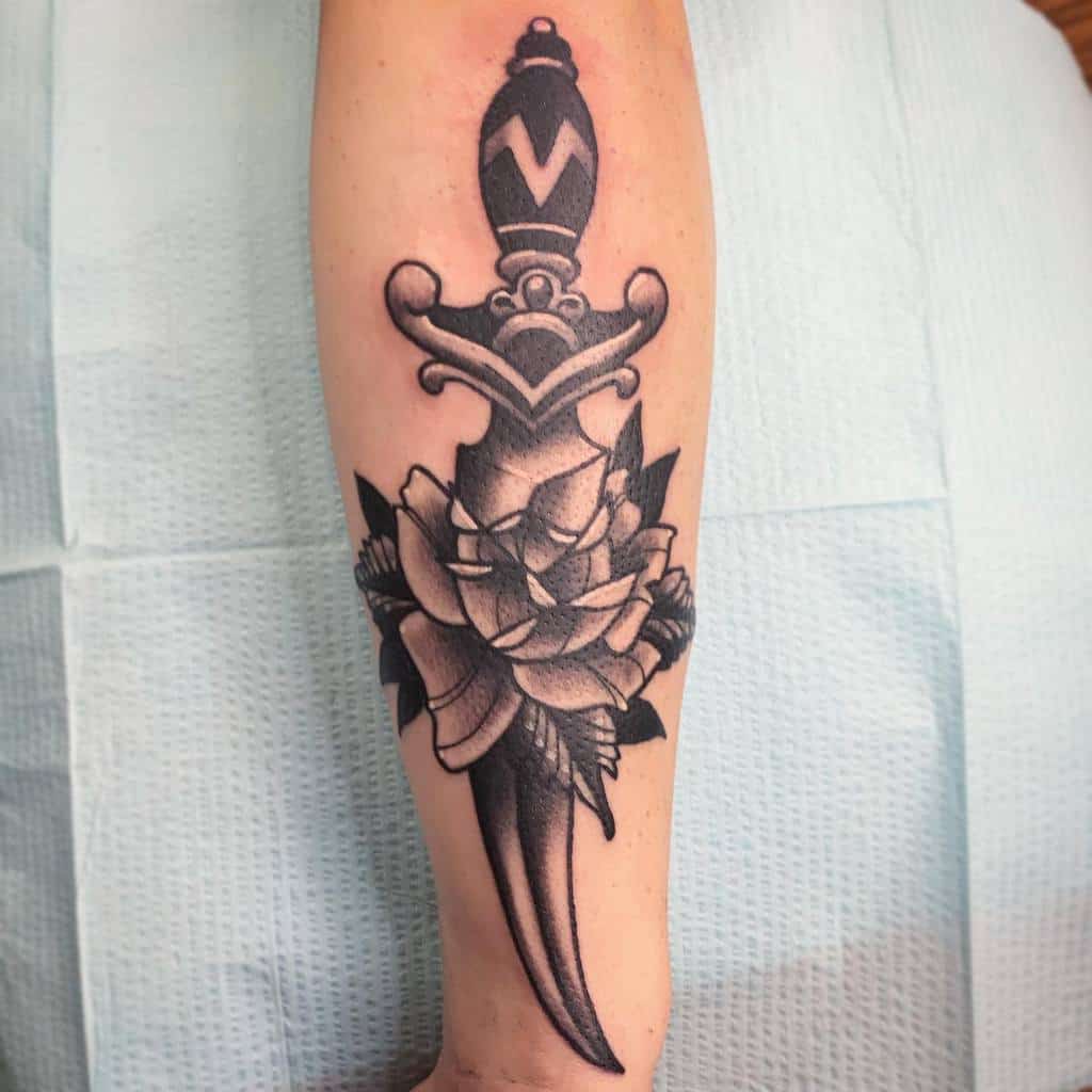 Tattoo of a dagger with a rose on an arm