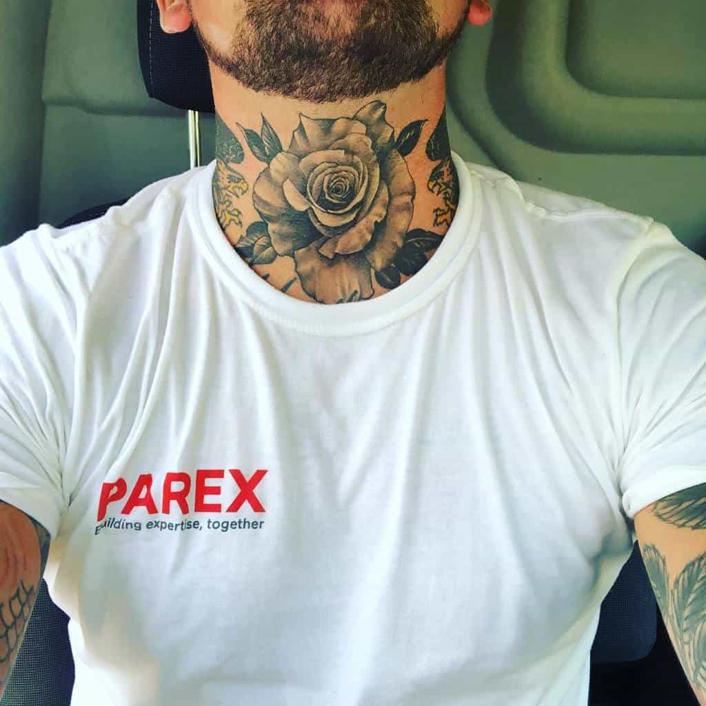 Intricate black and grey neck tattoo of a large rose with detailed petals and leaves, spanning the throat area