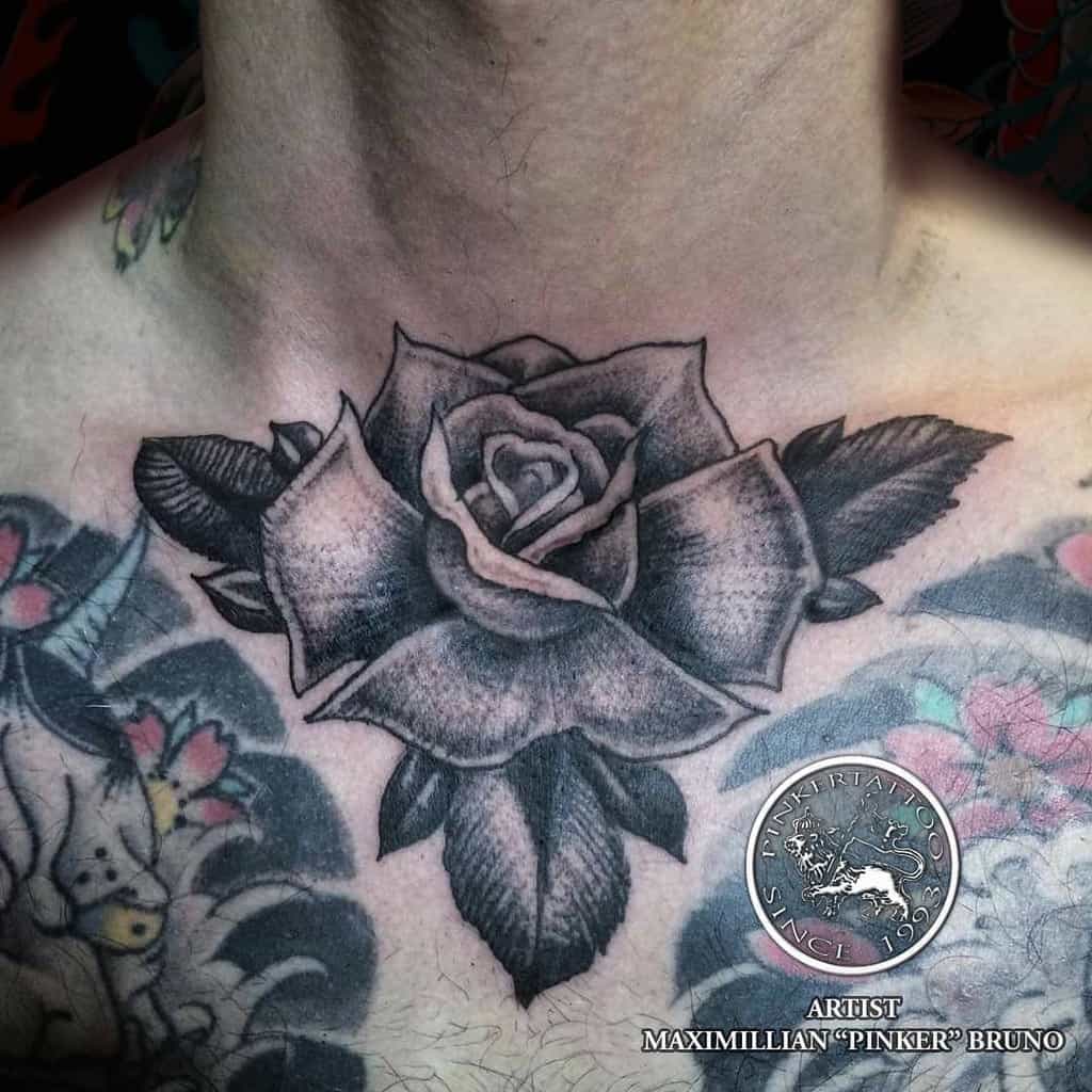 A beautifully intricate chest tattoo features a detailed rose intertwined with leaves, gracefully extending towards the neck