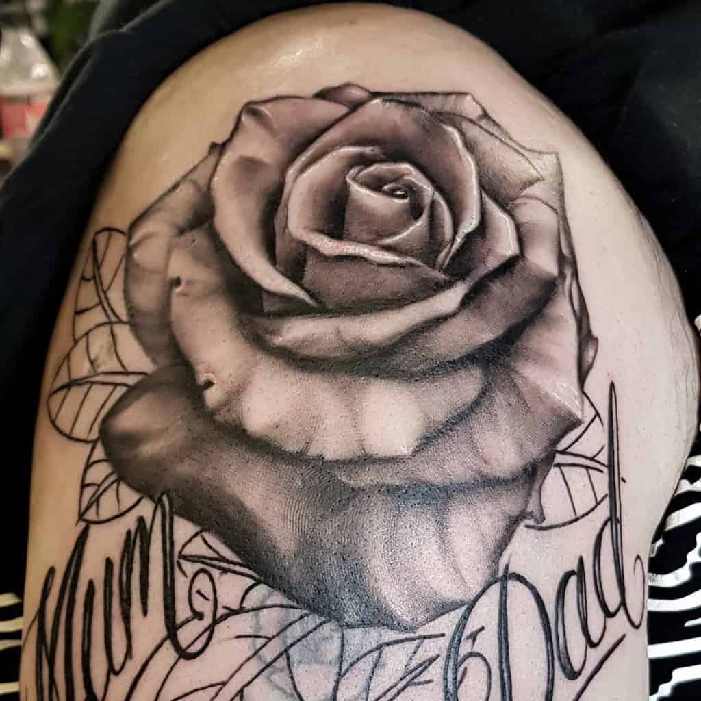 A tattoo of a detailed rose graces the shoulder, with "Mum" and "Dad" elegantly inscribed around it