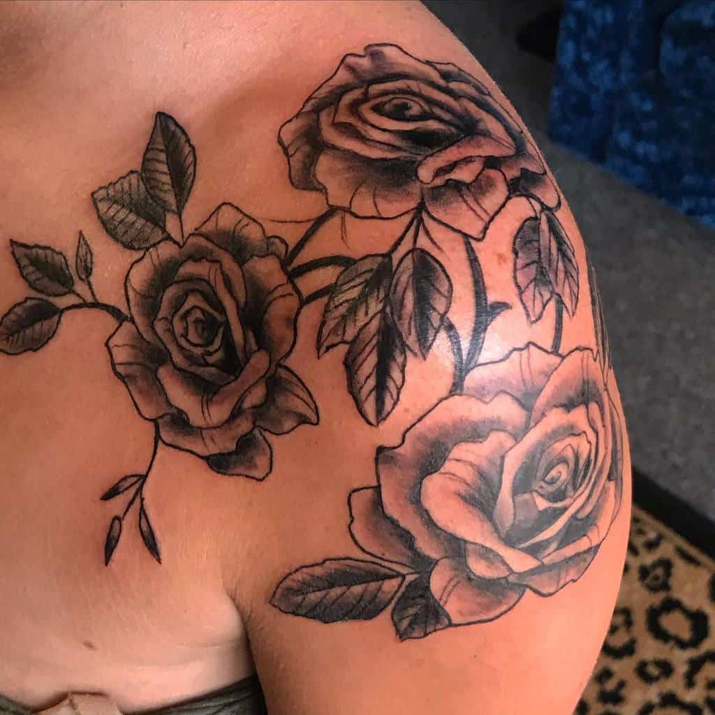 A striking shoulder tattoo of roses and leaves, intricately designed in black and gray ink