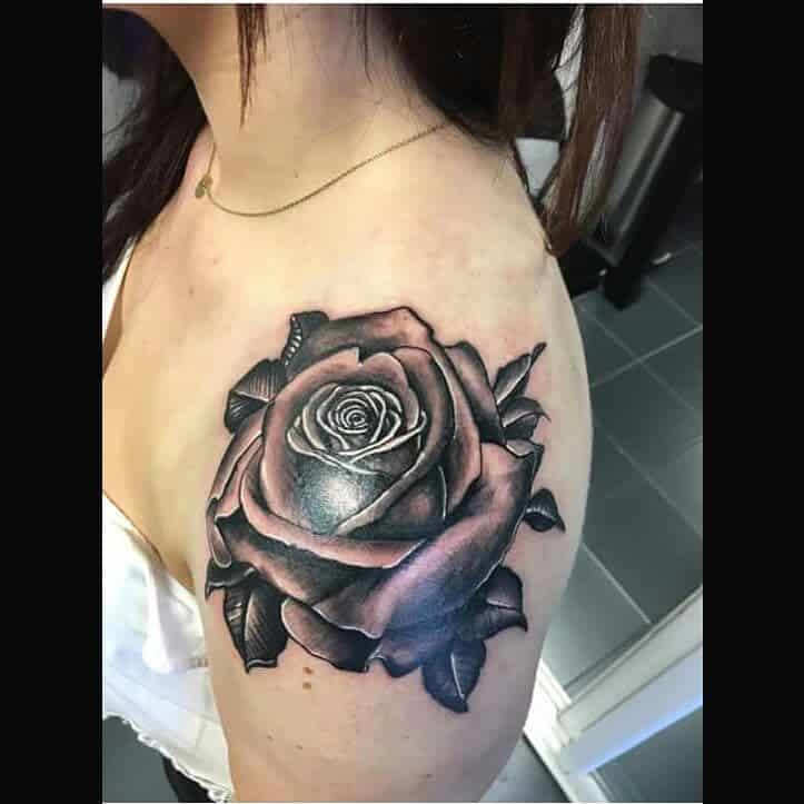 A detailed rose tattoo elegantly graces the woman's upper shoulder, adding a touch of artistry and flair