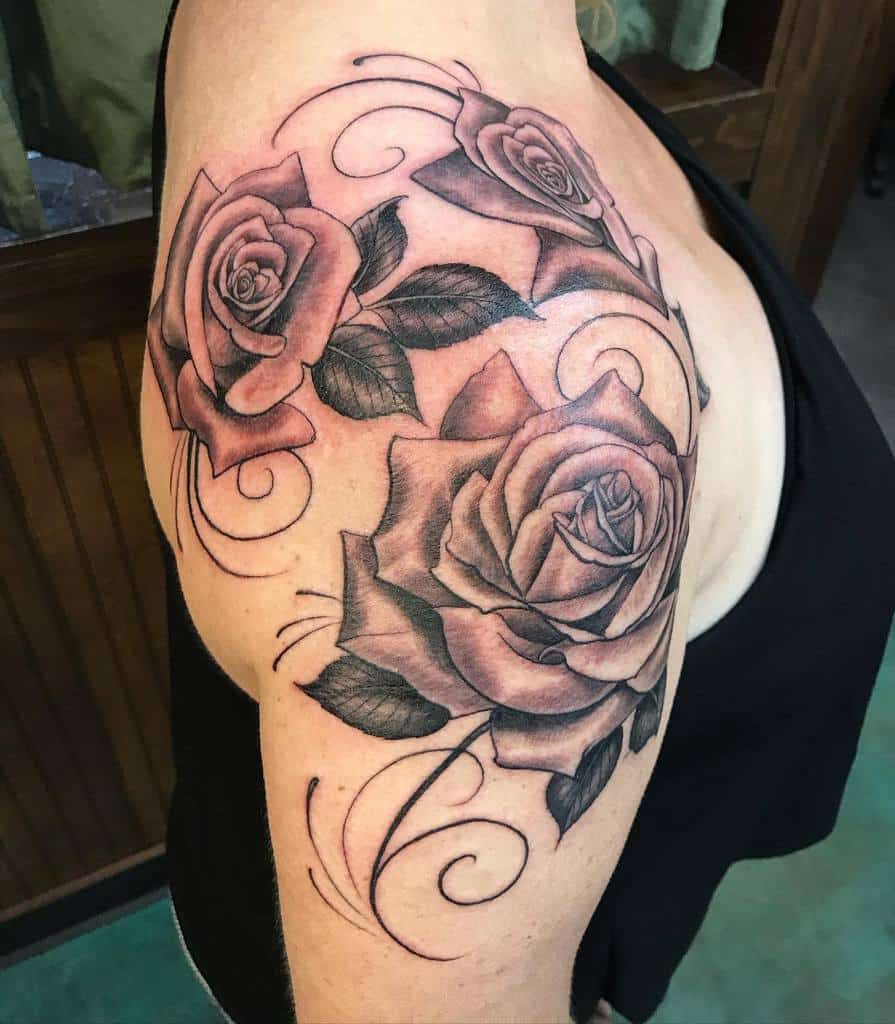 Tattoo of three detailed roses with swirling designs on an upper arm