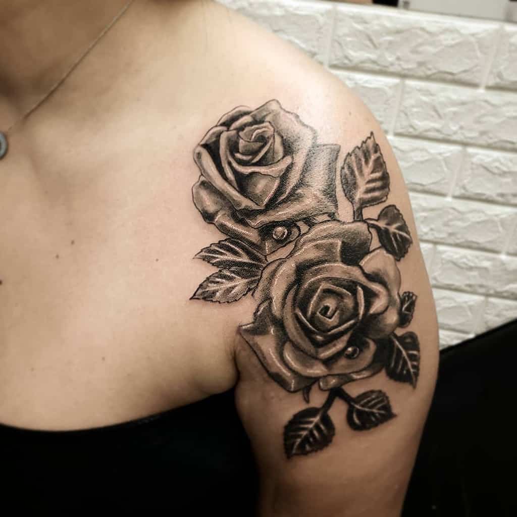A stunning tattoo of two intricately shaded roses, their delicate leaves cascading beautifully down the shoulder