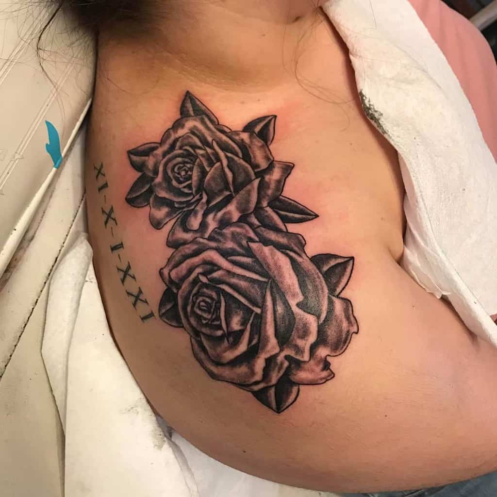 A tattoo of two roses intertwined with Roman numerals graces the shoulder