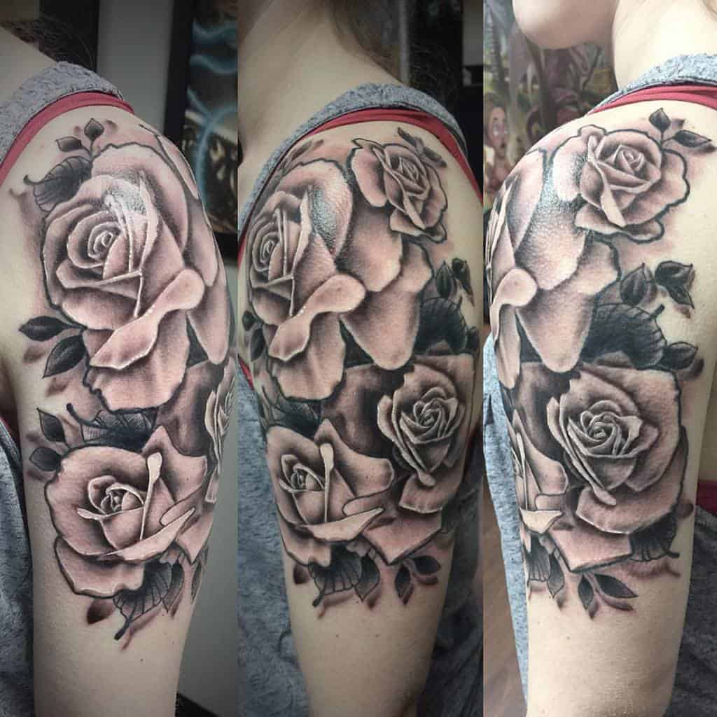 A stunning black and gray rose sleeve tattoo elegantly wraps around an upper arm