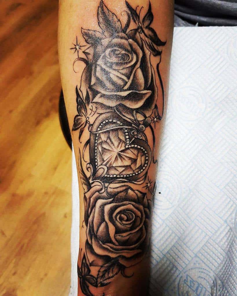 A stunning sleeve tattoo featuring roses intertwined with a jeweled heart design