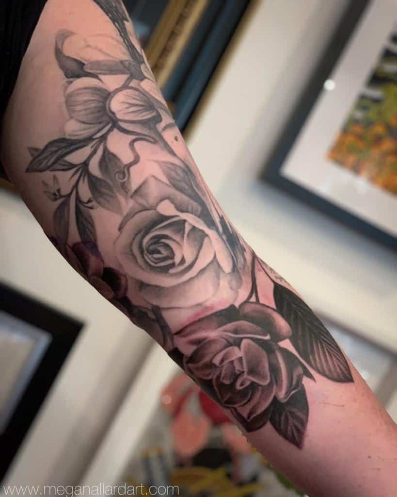 Stunning black and grey tattoo sleeve featuring intricately shaded roses, leaves, and delicate vines, creating a cohesive and elegant design along the arm