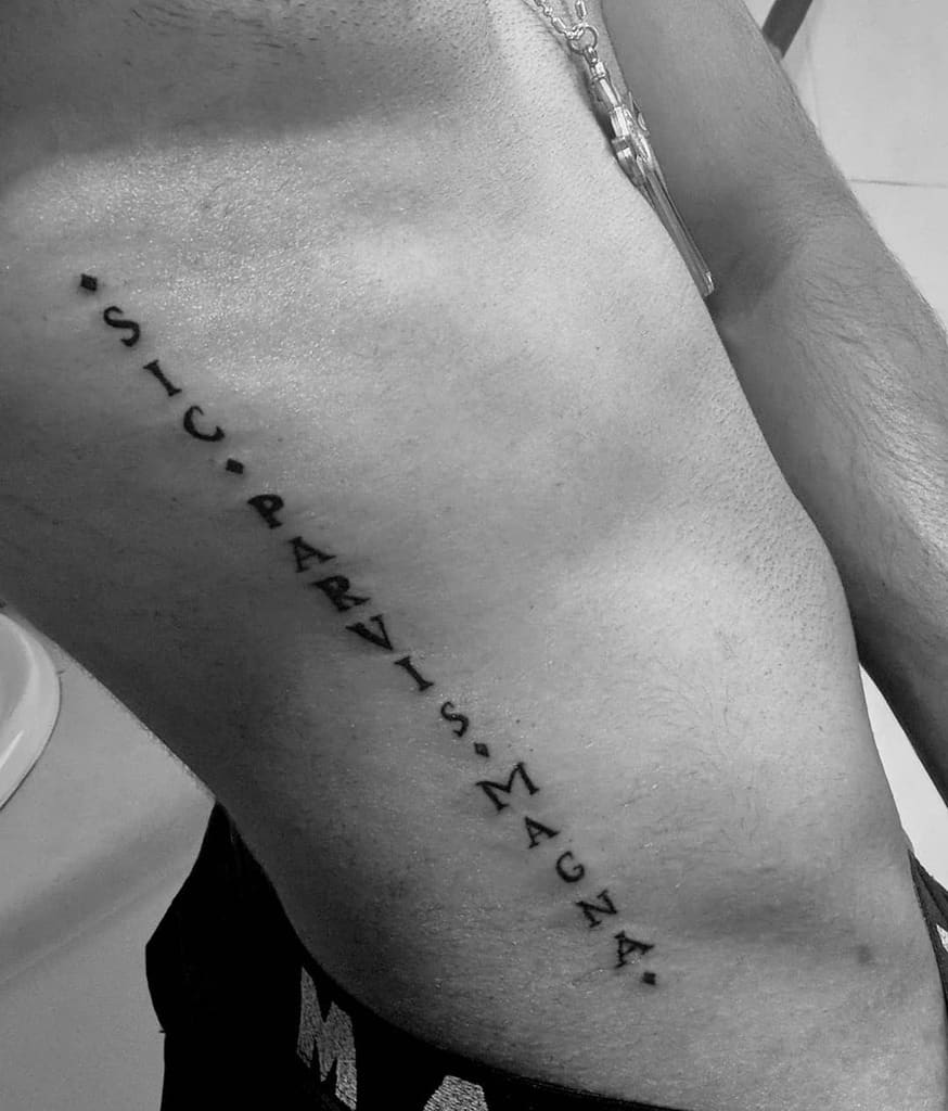 Side rib tattoo with 'Sic Parvis Magna' text in a minimalist vertical design, spaced by dots, in bold black ink