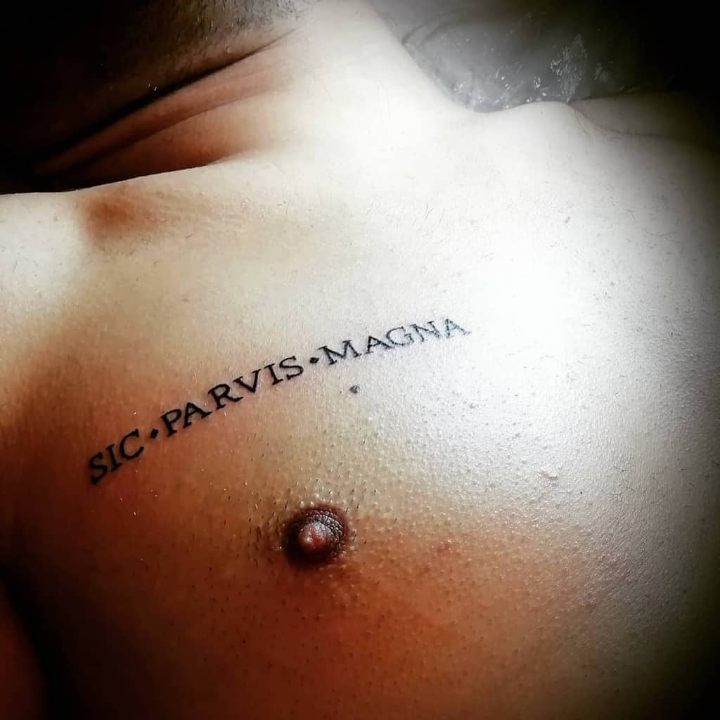 Tattoo on a person's skin reads "SIC PARVIS MAGNA" near the shoulder