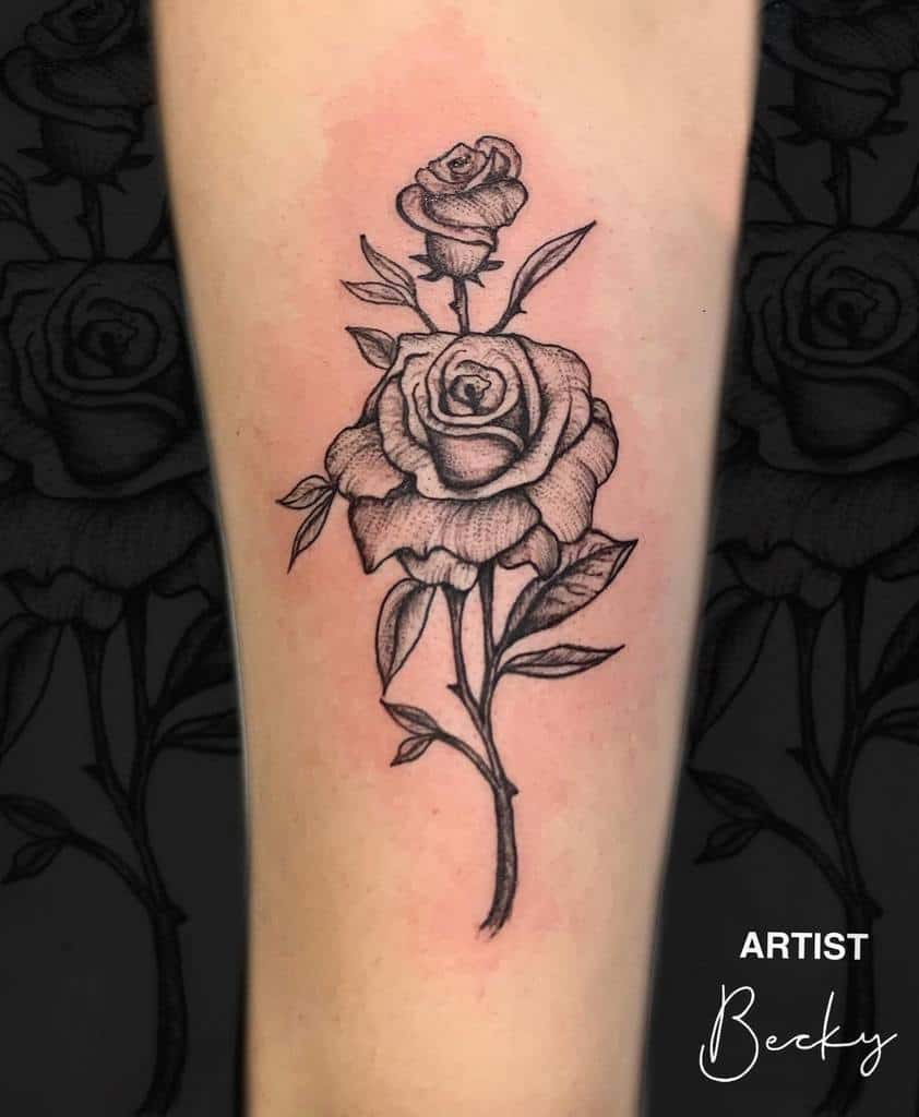 Black and gray rose tattoo with leaves on forearm