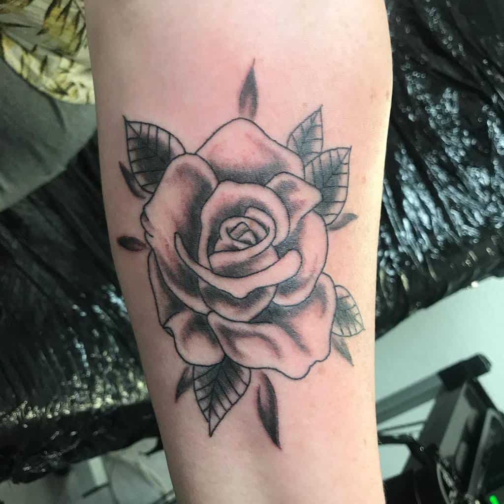 Black and gray rose tattoo on forearm with leaves