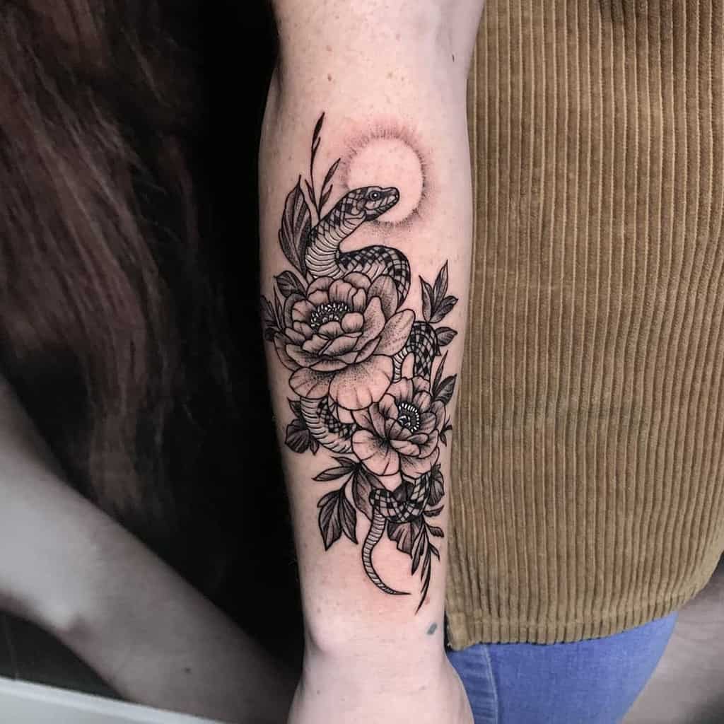 Forearm tattoo featuring a snake coiled around blooming flowers with leaves and a circular design
