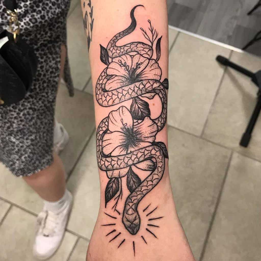 Arm tattoo of a snake entwined with flowers and leaves, with sunburst lines at the bottom