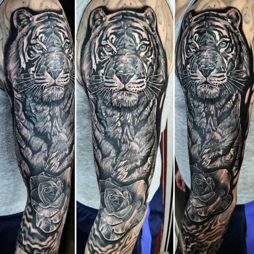 A stunning tattoo sleeve featuring an intricately detailed tiger intertwined with a lifelike rose, gracefully wrapping around the arm