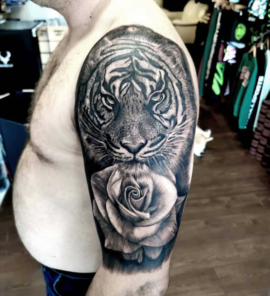 A stunning tattoo combines the ferocity of a tiger with the delicate beauty of a rose on a person's upper arm