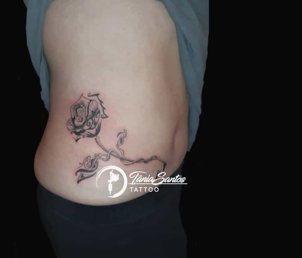 A stunning tattoo of a tribal-inspired rose with intricate vines gracefully adorning the person's side