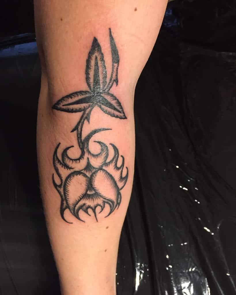 Arm tattoo of a stylized rose with sharp leaves and a flame-like design, featuring a touch of tribal artistry