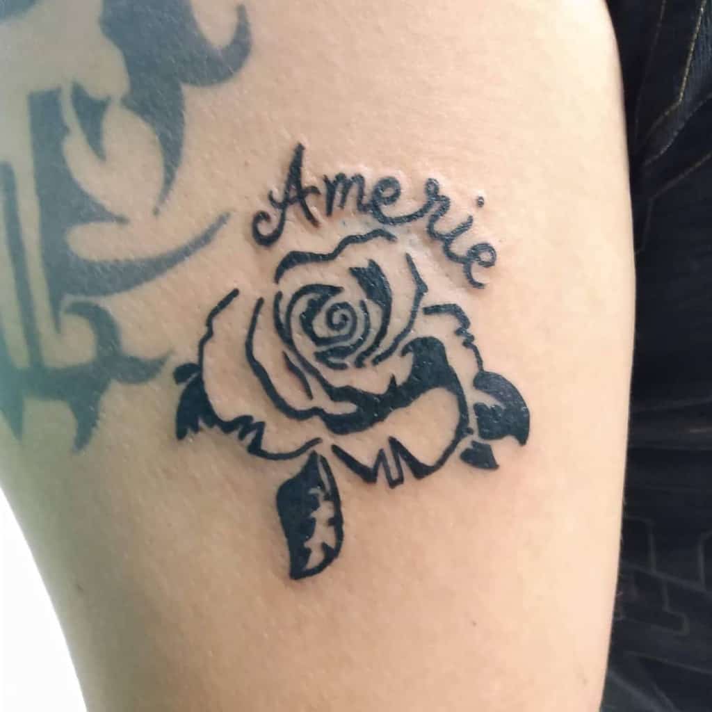 A stunning tattoo featuring a tribal rose intertwined with the name "Amerie" adorns the person's arm