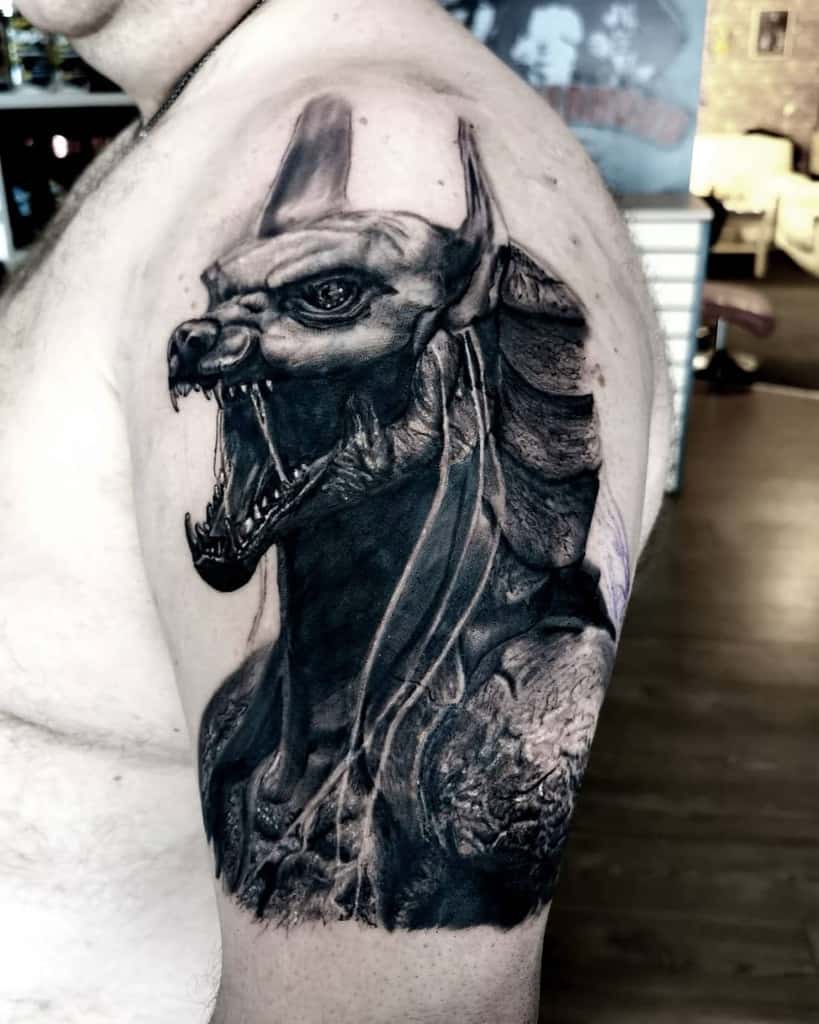 Tattoo of an Anubis-like figure with an open mouth on an upper arm