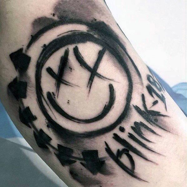 Black and gray tattoo of the Blink-182 smiley face logo with bold, dynamic brushstroke effects and the band's name "Blink-182" integrated into the design.