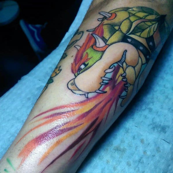 Bold Bowser tattoo on a man's arm, showcasing vibrant colors and dynamic shading as he breathes fiery flames in an intense action pose.