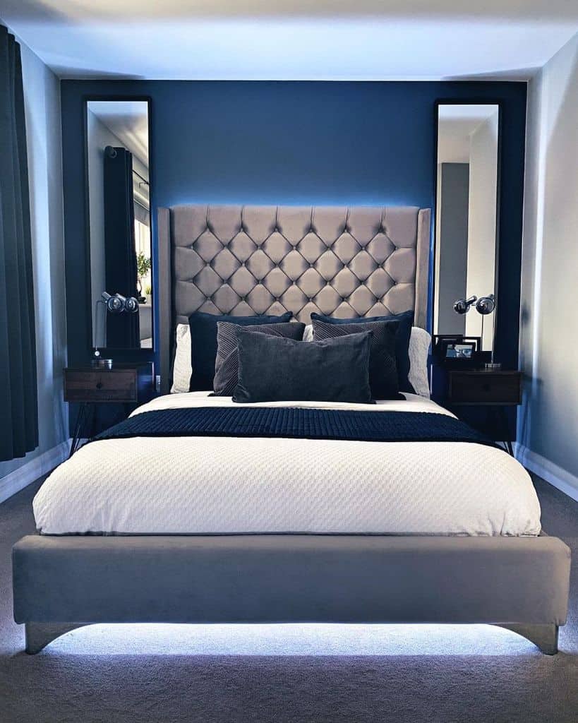 Modern bedroom with tufted headboard, blue accent wall, and soft LED lighting.