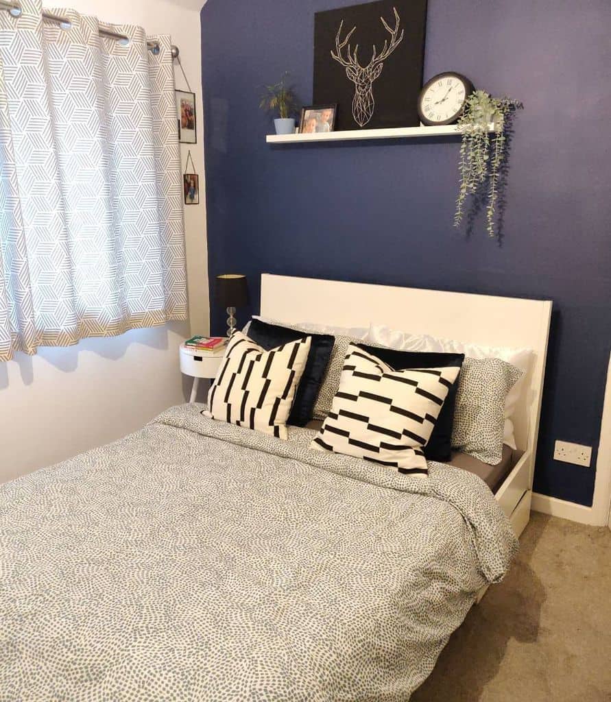 Small bedroom with navy blue accent wall, white bed, and black-and-white decor.