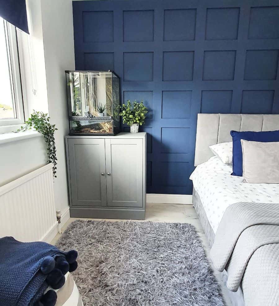 Bedroom with navy blue paneled accent wall, gray furniture, and soft decor accents.