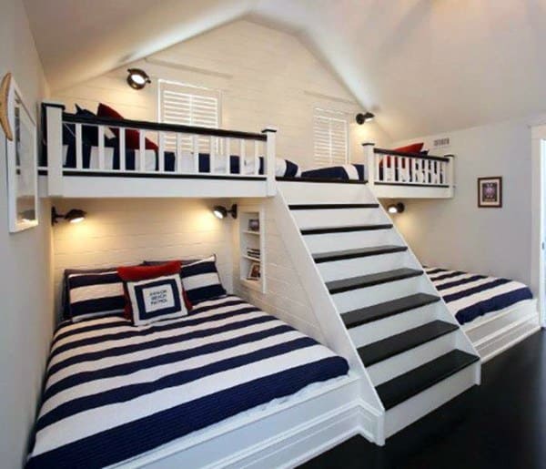Cozy bedroom with bunk-style loft spaces, accessed by central stairs, featuring nautical striped bedding on double beds