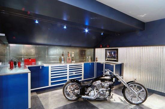 Modern garage with blue cabinets, metal backsplash, and a custom black motorcycle on display.