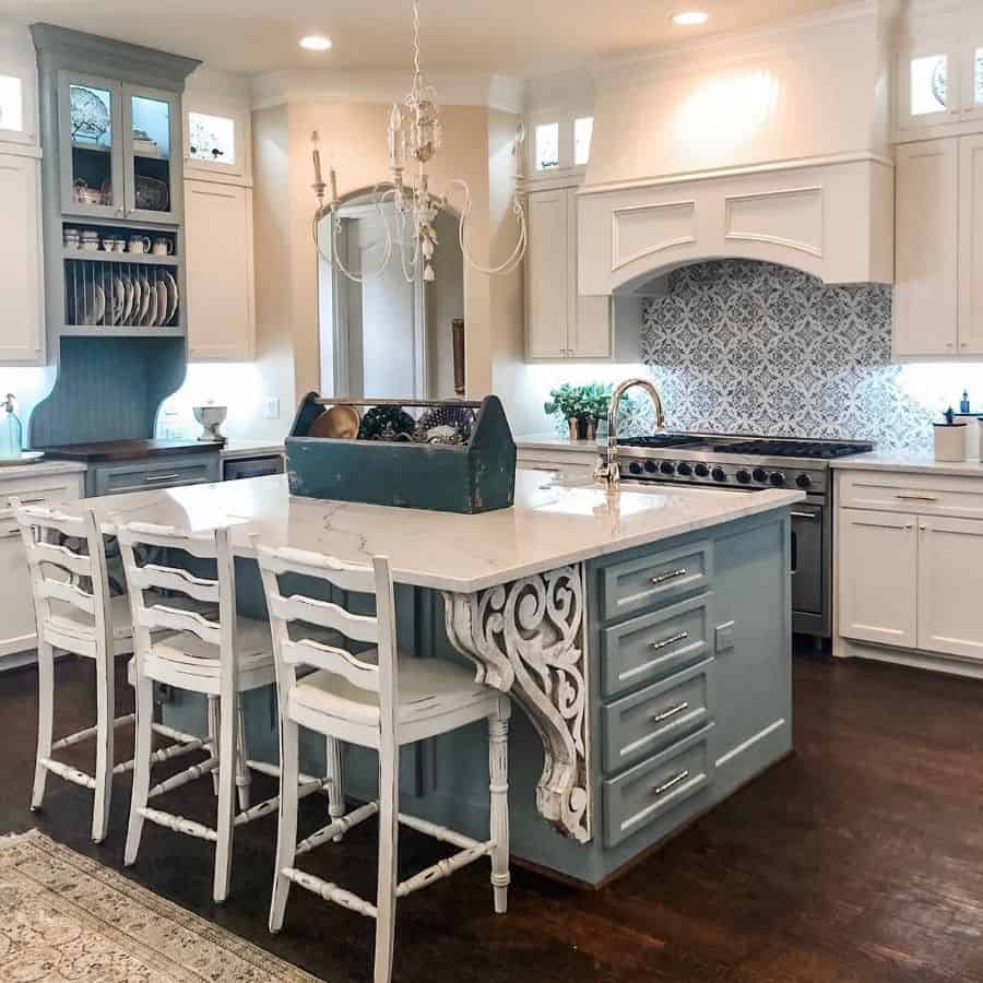 French country kitchen with blue island ornate details white cabinets and patterned backsplash.