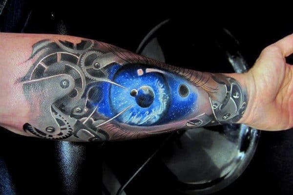 Forearm tattoo with a cosmic blue eye surrounded by mechanical gears and parts