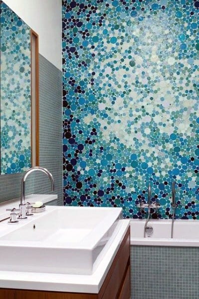 Bathroom with colorful blue mosaic dot tile accent wall and white sink.