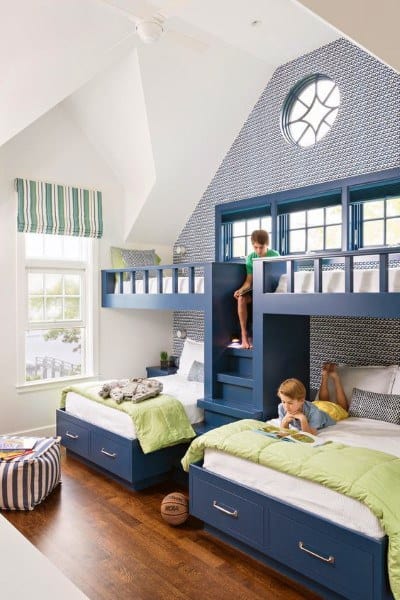Bright kids' room with blue bunk beds, green bedding, and high vaulted ceilings.