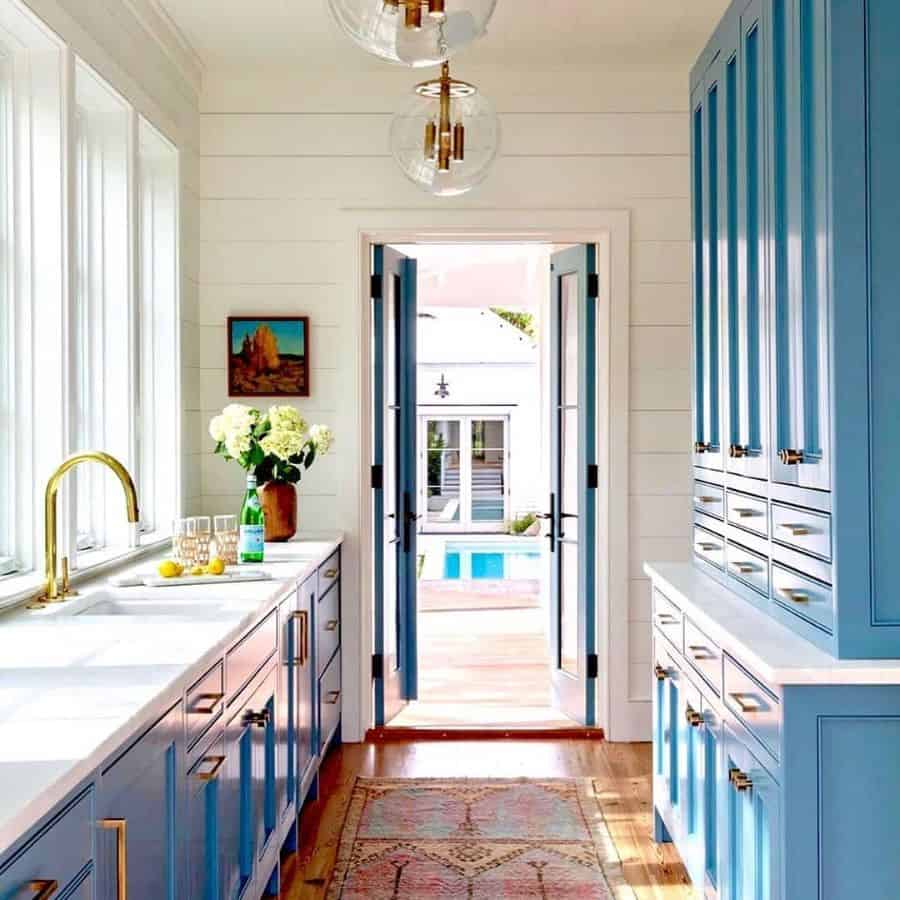 galley kitchen blue cabinets gold accents white marble bench top