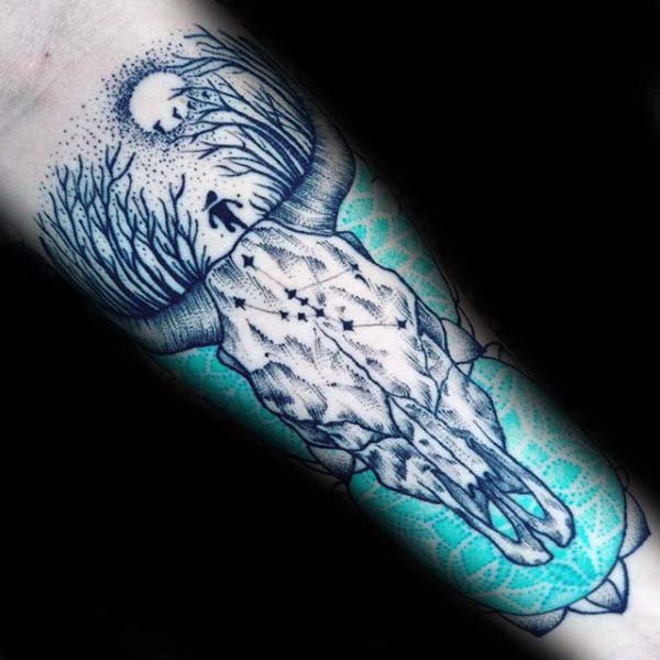 Forest and moon within bull skull tattoo with blue accents on forearm