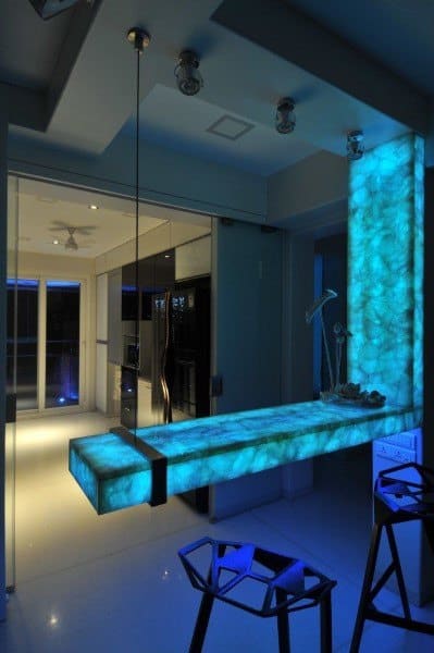 Futuristic bar with a glowing blue LED light top, suspended design, and sleek, transparent acrylic seating with a minimalist style.