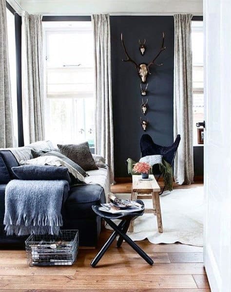 Navy and white living room with wooden floors, cozy sofa, and mounted antler decor. 