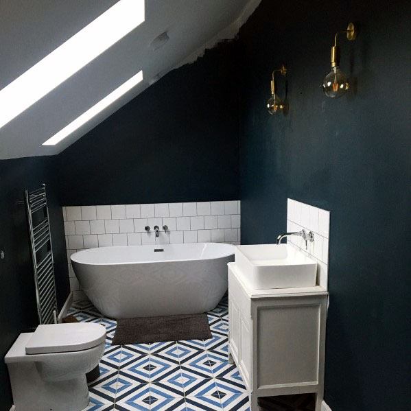 Bathroom with dark blue walls, white freestanding bathtub, patterned floor tiles, and white vanity sink.