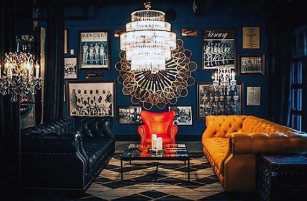 Stylish room with chandeliers, leather sofas, vintage photos, and a red armchair around a central coffee table