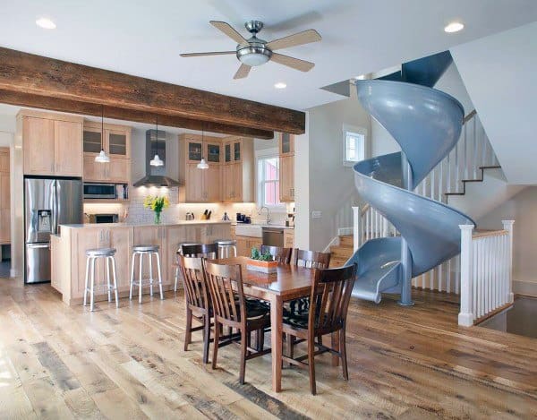 Open kitchen with wooden cabinets and dining area, featuring a spiral slide adjacent to the staircase