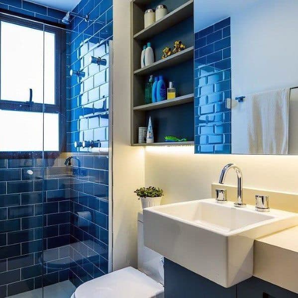 Bathroom with blue subway tiles, glass shower, and modern white sink.