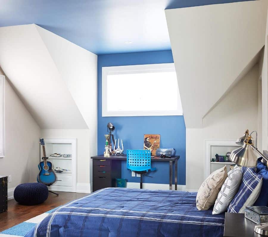 Modern blue kids' bedroom with study desk, guitar decor, and blue bedspread.