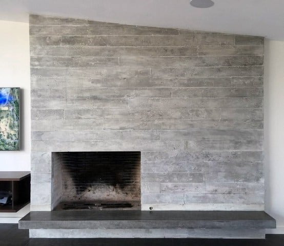 Board-formed concrete fireplace with a minimalist design and dark gray hearth.