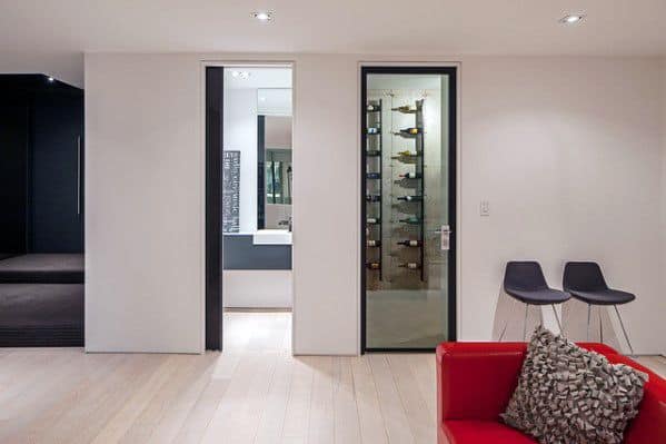 Modern living space with light wood flooring, wine storage, and minimalist baseboards.