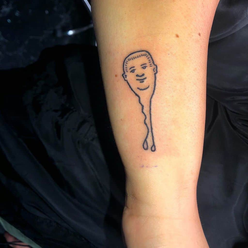 A black ink tattoo of a melting key-shaped figure with a cartoonish face, blending surrealism with humor in a minimalist style.